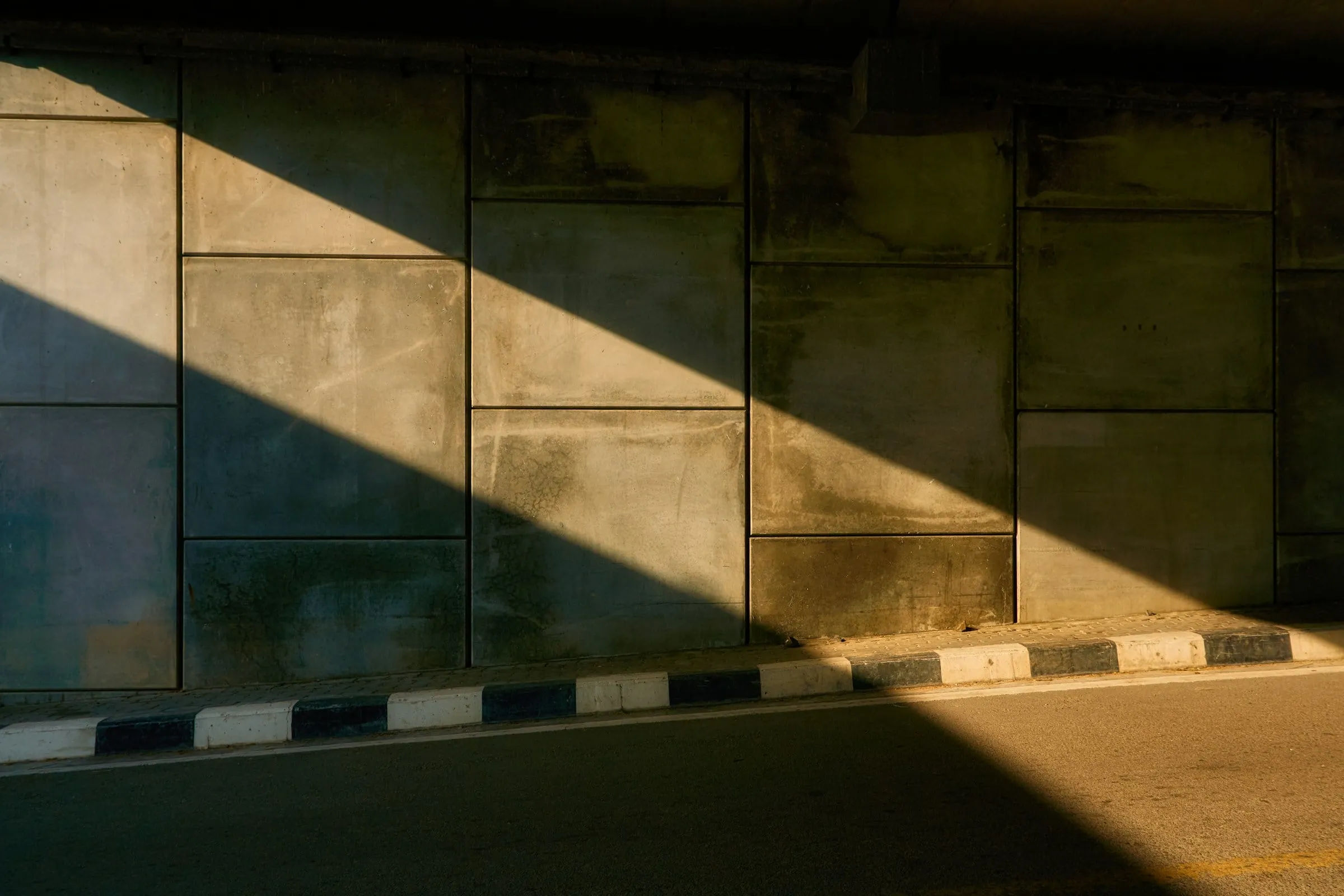 Sunlight casting a diagonal shadow across a concrete wall